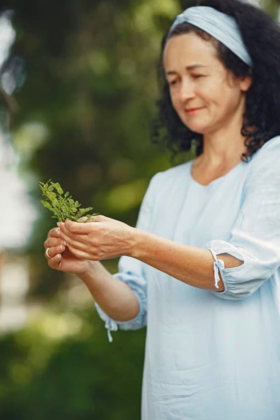 A practitioner holding a sprig of fresh herbs